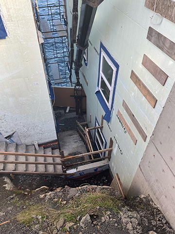 materials being delivered in a tight space between two buildings